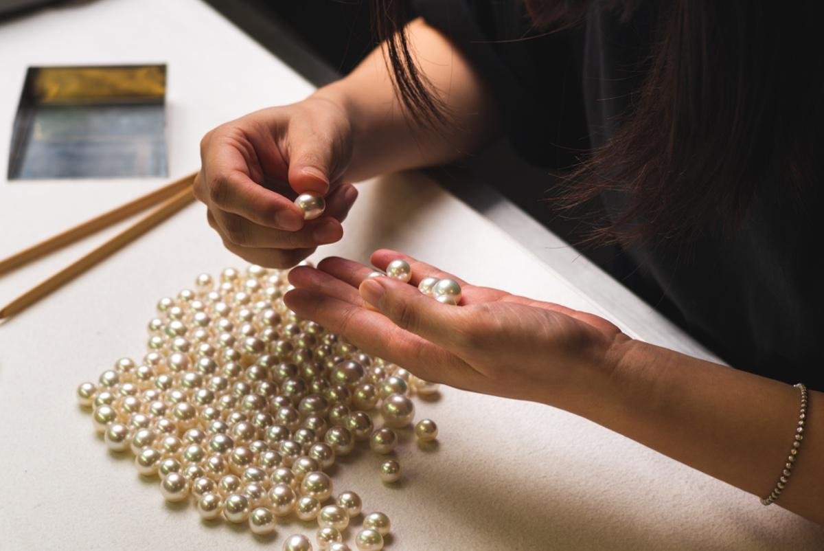 Hands selecting pearls from the collection